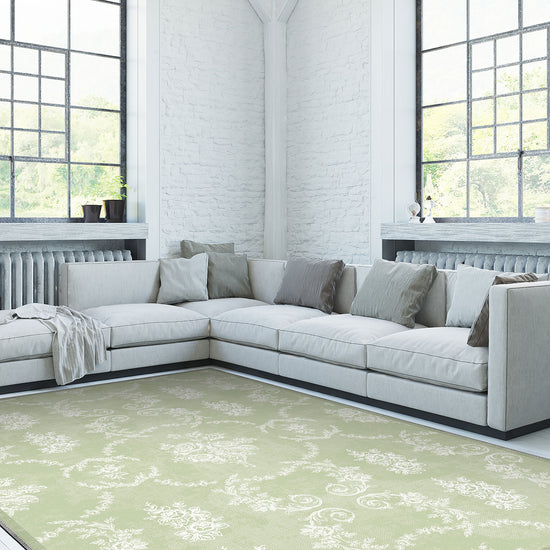 Modern living room with a light gray sectional sofa and a green patterned rug.