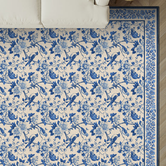Blue and white floral and bird patterned rug on a wooden floor.
