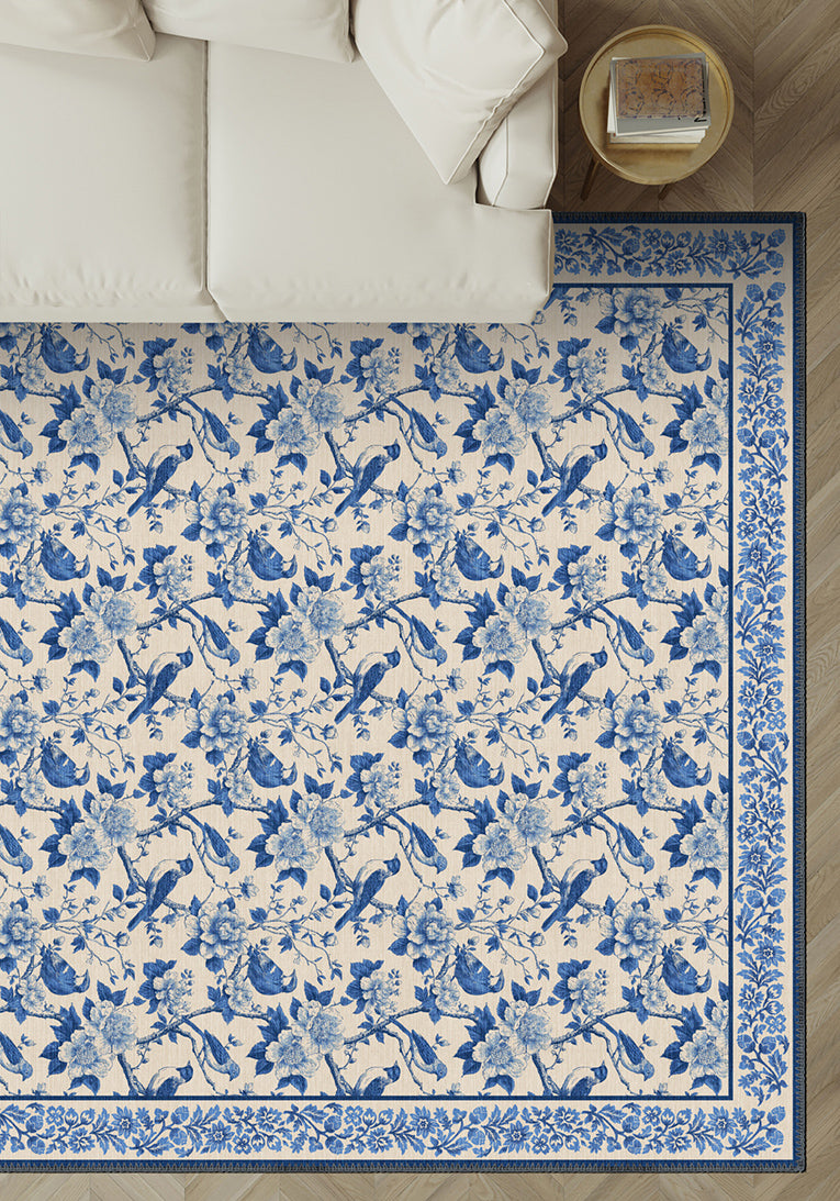 Blue and white floral and bird patterned rug on a wooden floor.