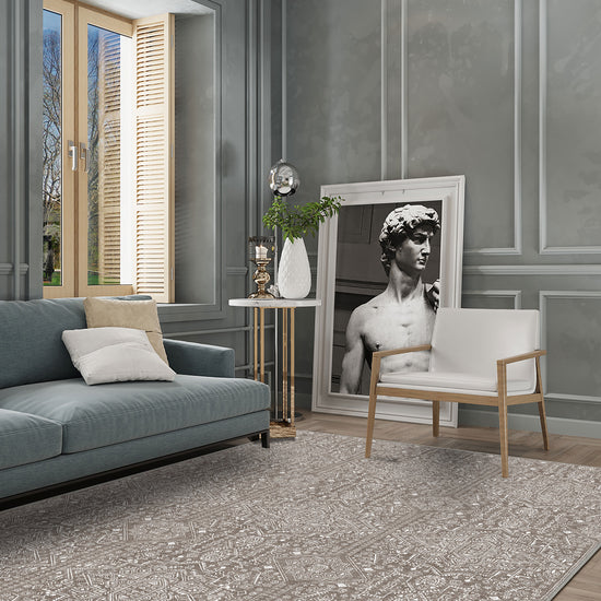 Modern living room with gray walls, a gray sofa, and a decorative rug.